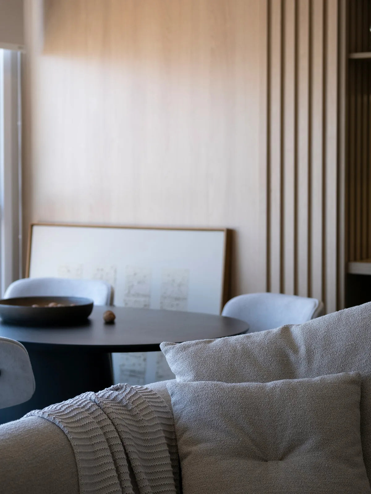 A quiet living room with a framed picture leaning against the wall.