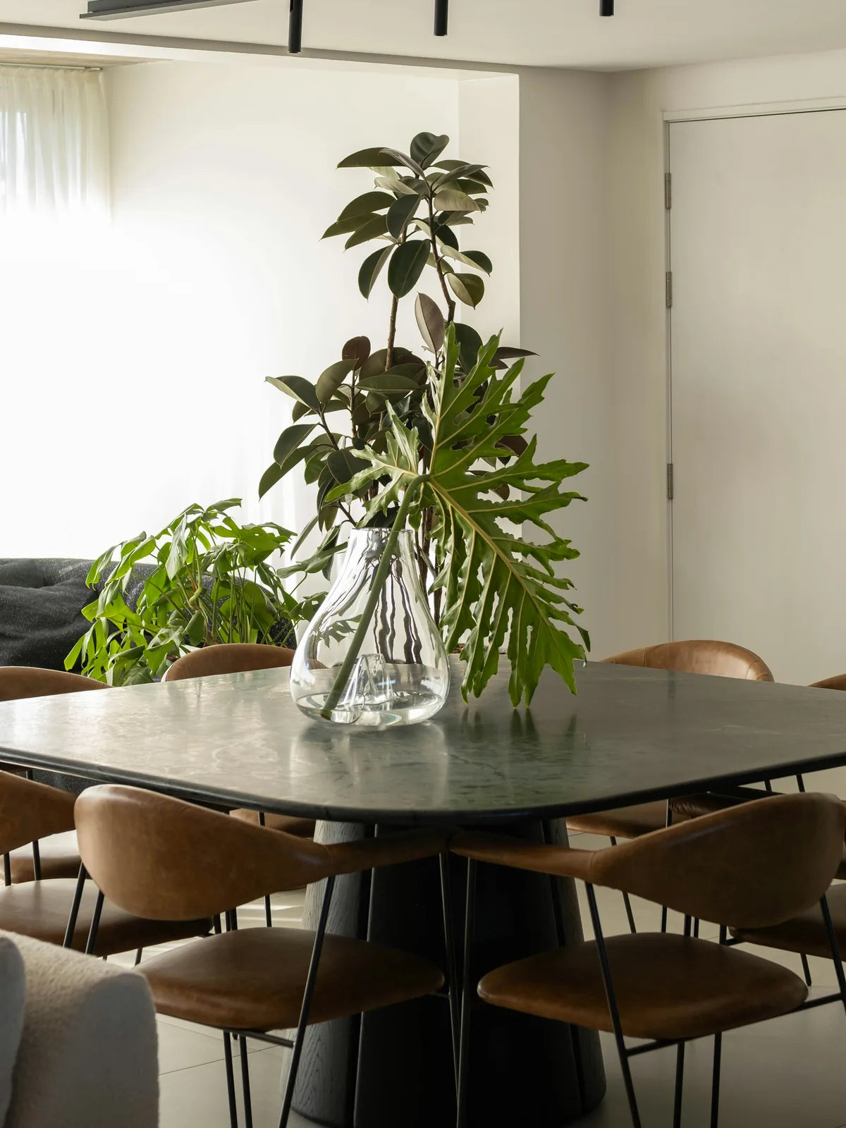 Eight leather chairs set around a green marble dining table, with clear space to pull each one out.