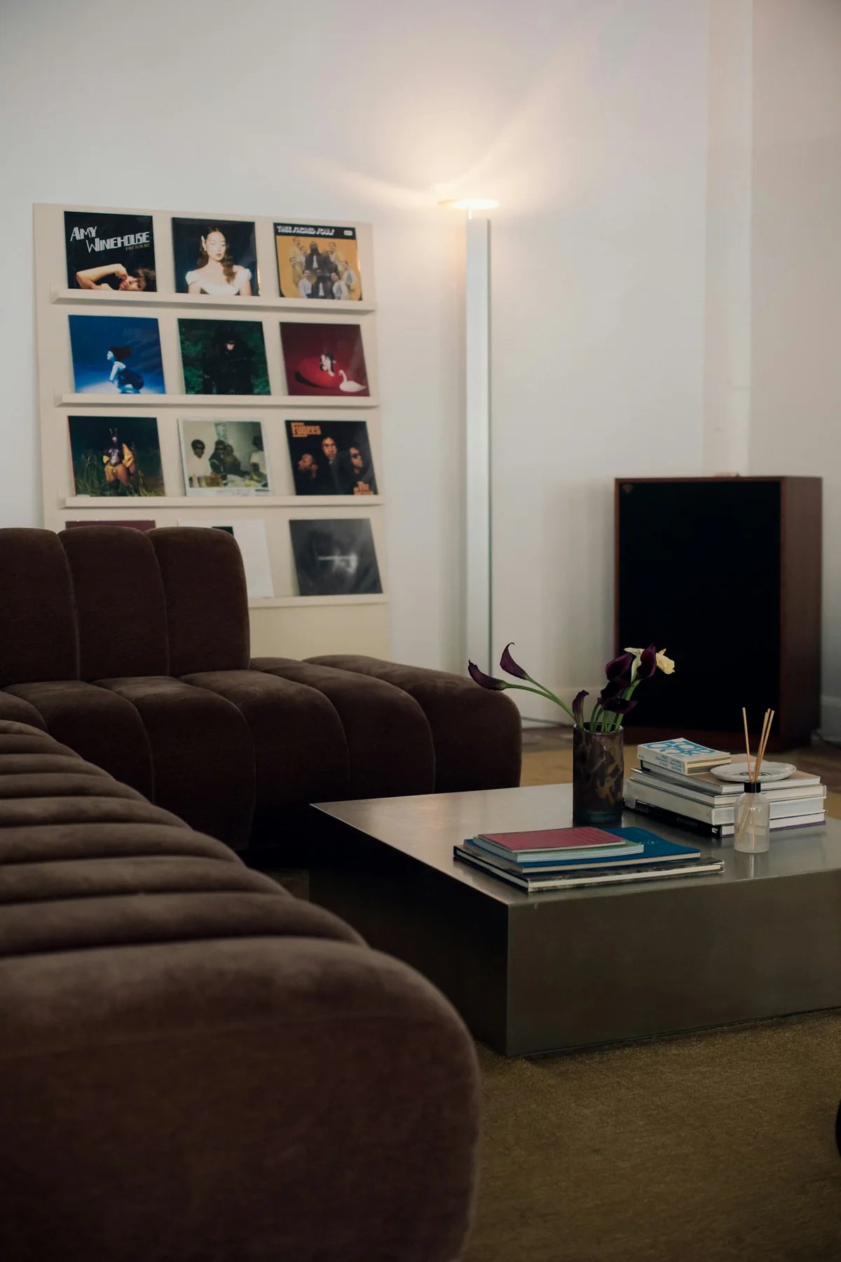 Chocolate brown sectional seating, a low chrome table and records displayed on the wall.